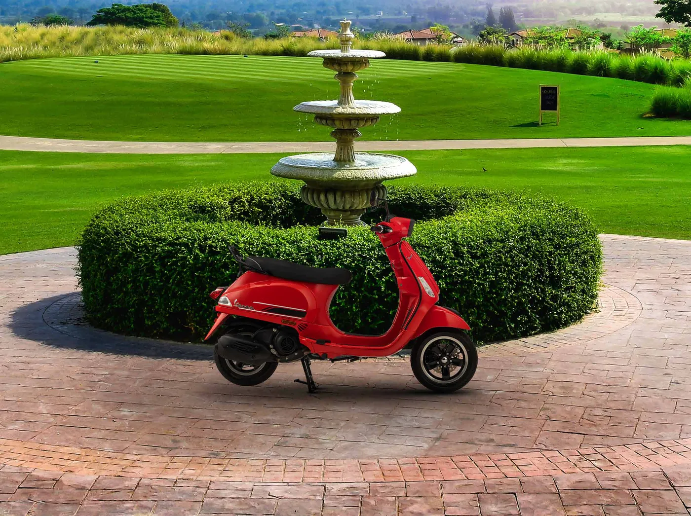 Red Vespa S beside a garden fountain